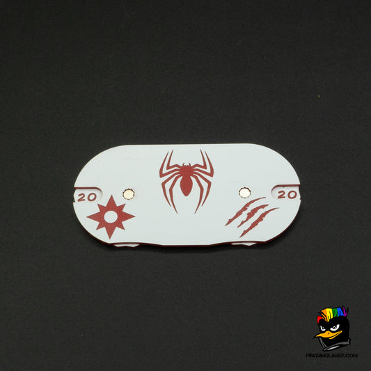 Dial blanco alargado con grabado en rojo. En el lado izquierdo tenemos el contador de poder representado con una estrella de ocho puntas. Al lado derecho, el contador de heridas representado por unas marcas de arañazos. En el centro la araña de Spiderman.