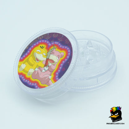 Grinder personalizado con una imagen inspirada en pokemon: psyduck y slowpow están sentados uno al lado del otro compartiendo una pipa. El grinder es transparente y se muestra abierto.