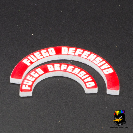 Dos marcadores de metacrilato con el texto "fuego defensivo" en tipología de Punkapocalyptic. El de arriba es para peanas de 40mm y el de abajo para peanas de 25mm. Son de color rojo con las letras en blanco. Se ponen junto a la peana, ya que la forma curvada de los marcadores se ajusta a la circunferencia de la misma.