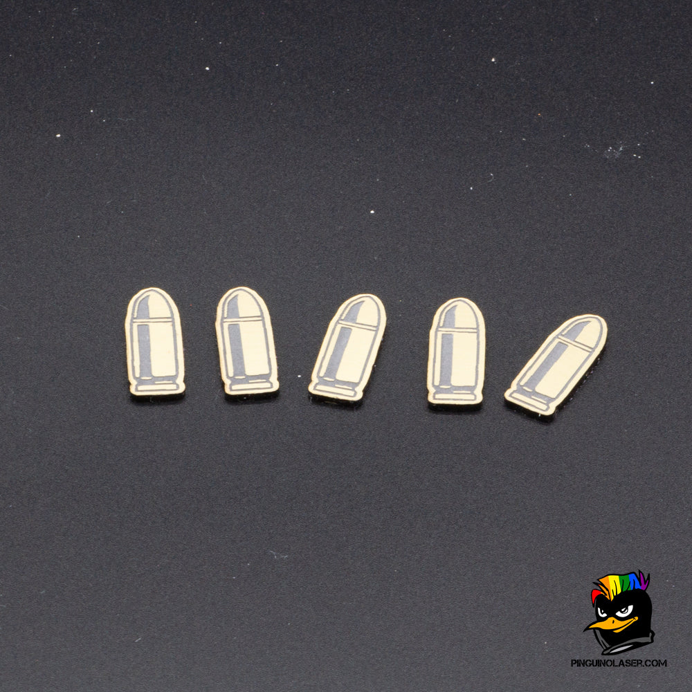 Foto grupal de cinco balas en metacrilato dorado con grabado en negro. 