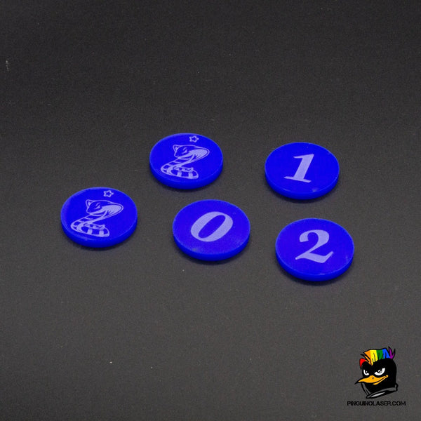 Foto de conjunto de  5 marcadores de objetivo de Kings of War de color azul sólido. Están grabados en láser con los números 1, 2 y 0. También hay dos marcadores grabados con una serpiente como ejemplo de personalización para la parte superior.