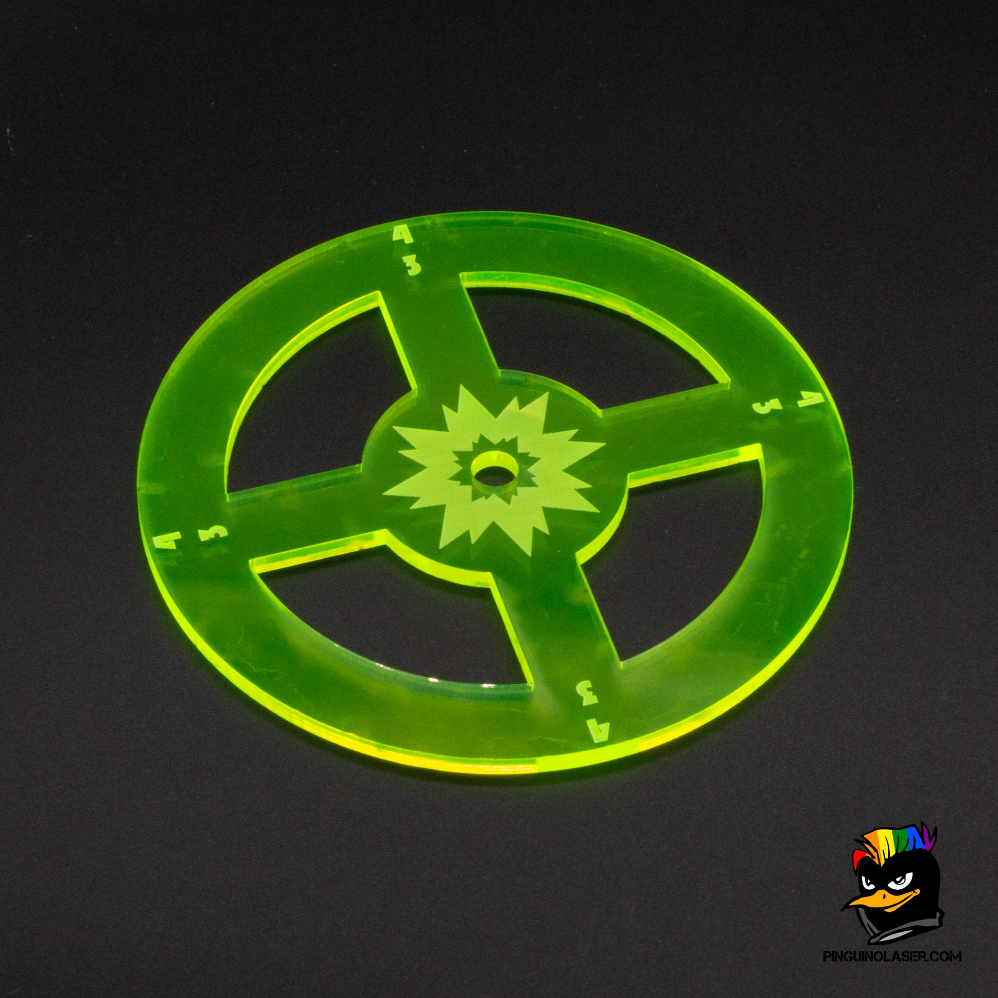 Foto de plantilla de explosión en metacrilato verde translúcido. Tiene forma redonda, pero esta cortado en el centro formando una cruceta con otro círculo dentro con grabado de explosión.