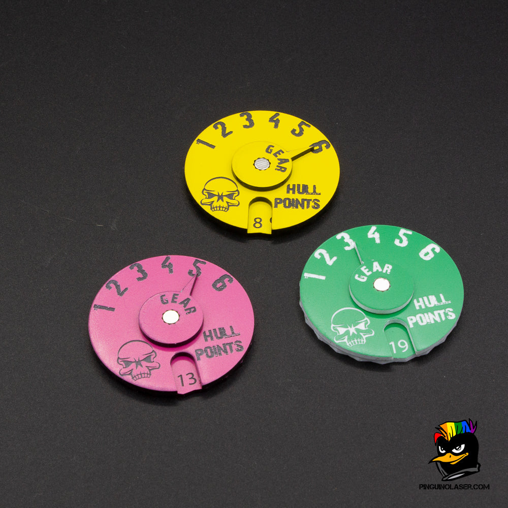 En la foto aparecen tres diales de gaslands en color rosa con grabado en gris, verde con grabado en blanco y amarillo con grabado en gris.