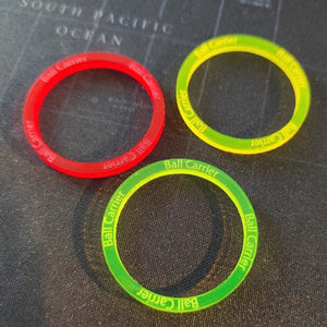 Foto de conjunto de tres Ball Carrier Ring, formando éstos un triángulo. Uno es rojo, otro amarillo y otro verde. Todos en metacrilato en colores flúor