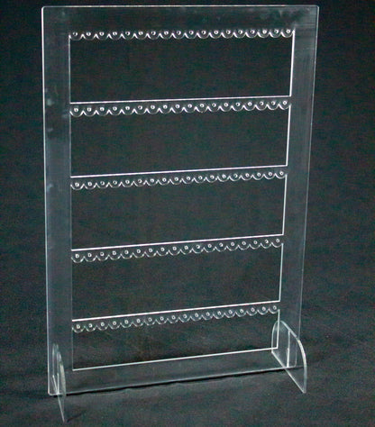 Joyero expositor para pendientes en metacrilato transparente. Es un rectángulo con tres filas en el interior con agujeros para colocar pendientes. 